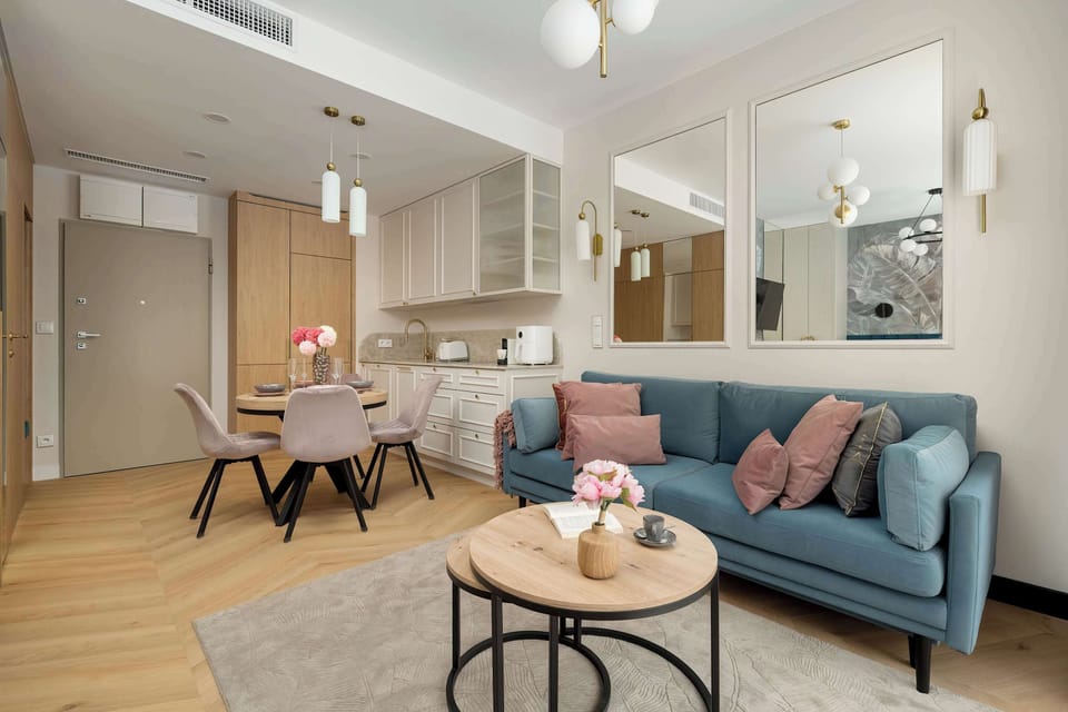 Open-plan studio with teal sofa next to large floor-to-ceiling curtains.