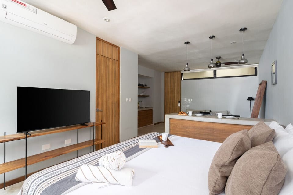 Cozy studio with a comfy bed, wooden accents, and a sleek TV setup.