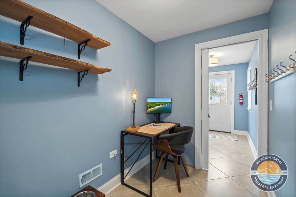Dedicated home office with a floating desk, monitor, ergonomic setup, and calming blue accent walls — perfect for remote workers who need to stay productive while enjoying a Lake Geneva vacation! High-speed WiFi & fast internet included!