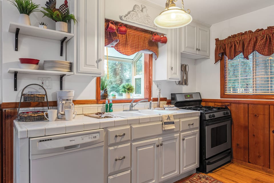 Close-up of the kitchen counter area with white cabinets, a sink, and a stove/oven.