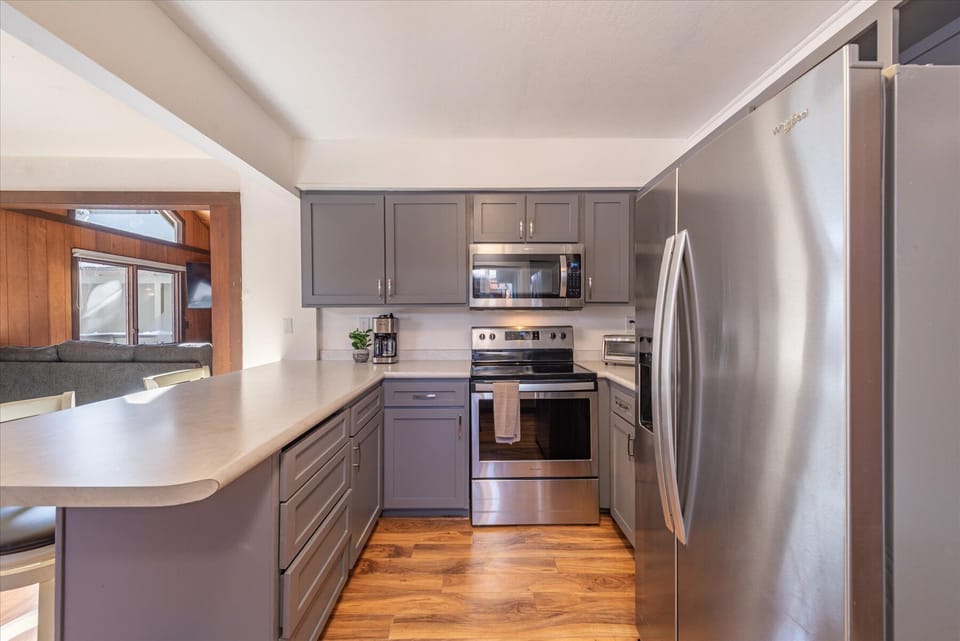 You'll love preparing meals in this sleek, fully-equipped kitchen featuring stainless steel appliances and modern gray cabinetry.