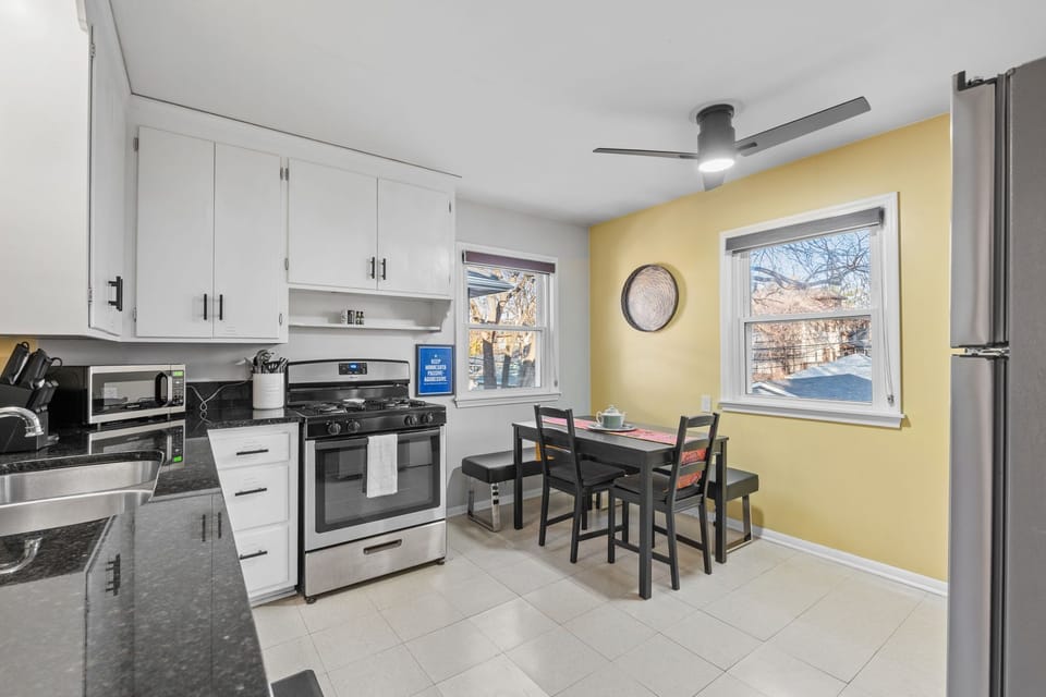 Your fully-equipped kitchen invites morning coffee rituals with warm yellow walls, modern appliances, and a cozy dining nook bathed in natural light.