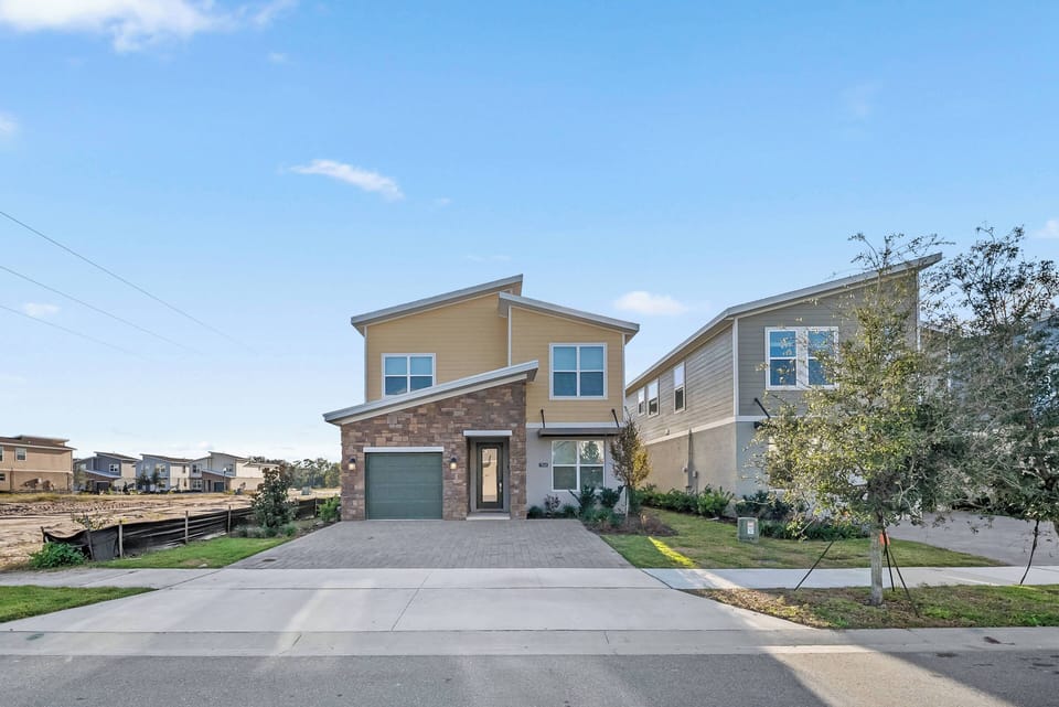 This stylish home boasts a warm yellow exterior with natural stone accents, inviting you to discover its cozy interior. Large windows fill the space with natural light, creating a welcoming atmosphere for guests to enjoy.
