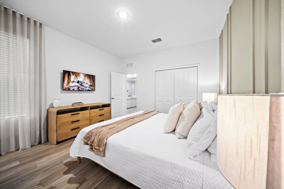 Step into a cozy bedroom featuring soft, neutral tones that create a calm atmosphere. The plush bedding and large, inviting headboard complement the warm wood accents, while the stylish lighting adds a touch of modern comfort.