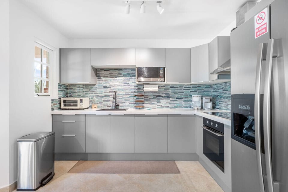 Modern kitchen with new appliances, including oven, refrigerator/freezer, microwave, coffee maker, and essentials.