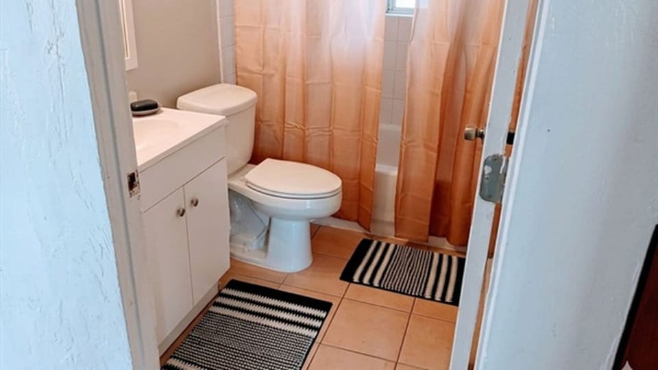 Bathroom with toilet, vanity, and shower curtain