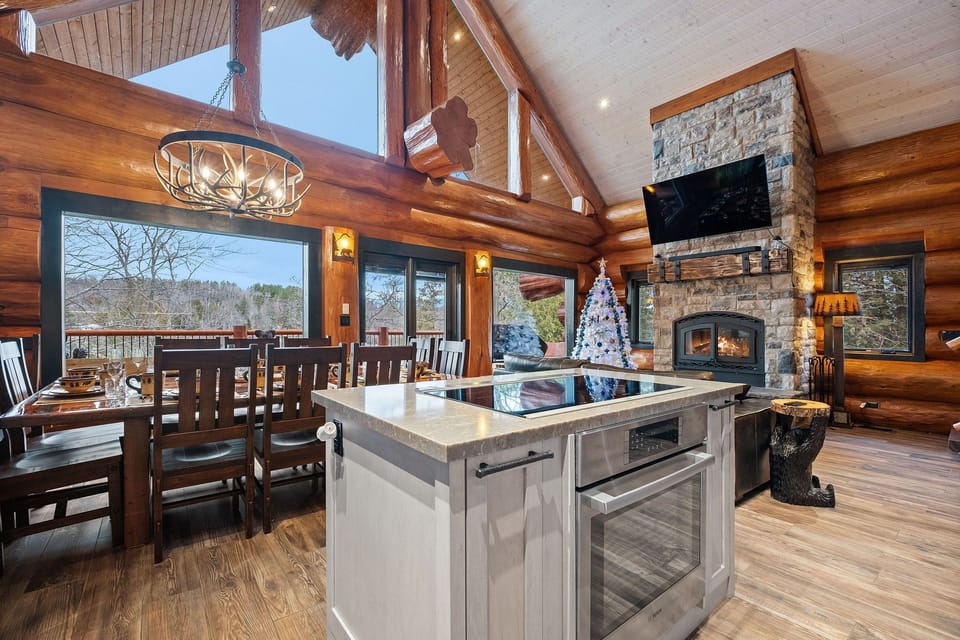 Beautiful dining space with seating for large groups, stone fireplace, and a fully equipped gourmet kitchen with island.