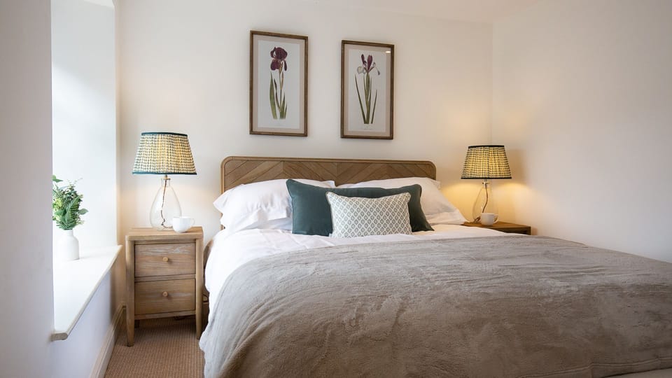 Matching wooden bedside tables and a chest of drawers furnish the room.