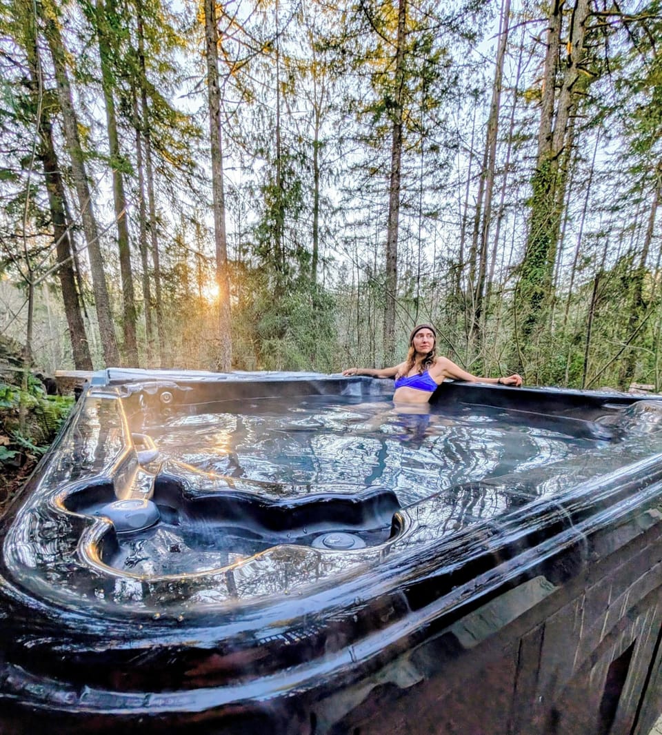 Large hot tub surrounded by forest, with a glimpse of the river