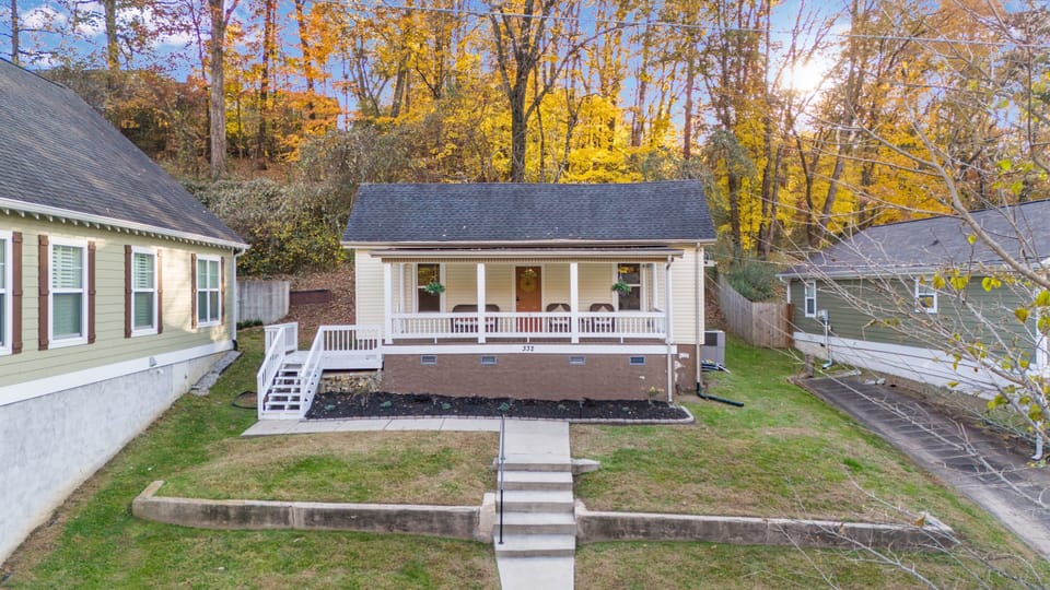 View of Sylvan House with a large porch, chairs, and a landscaped yard.