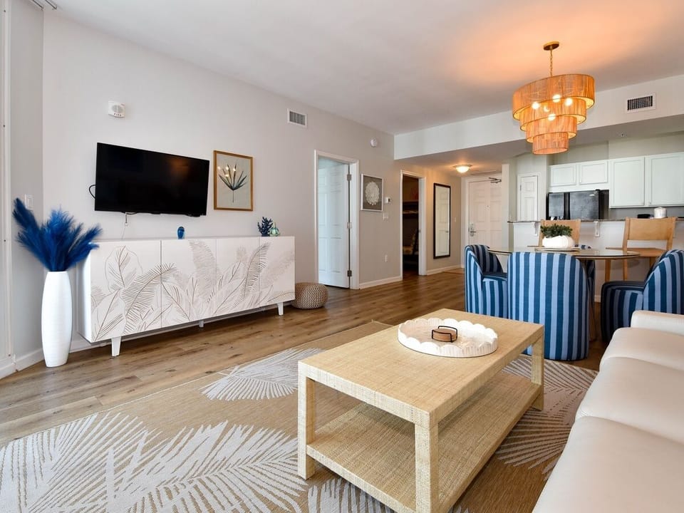 Stylish living area w/ modern decor, warm lighting, and an open flow into the kitchen.