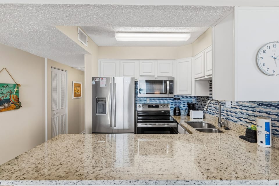 This modern coastal kitchen features granite countertops and sleek stainless-steel appliances. 