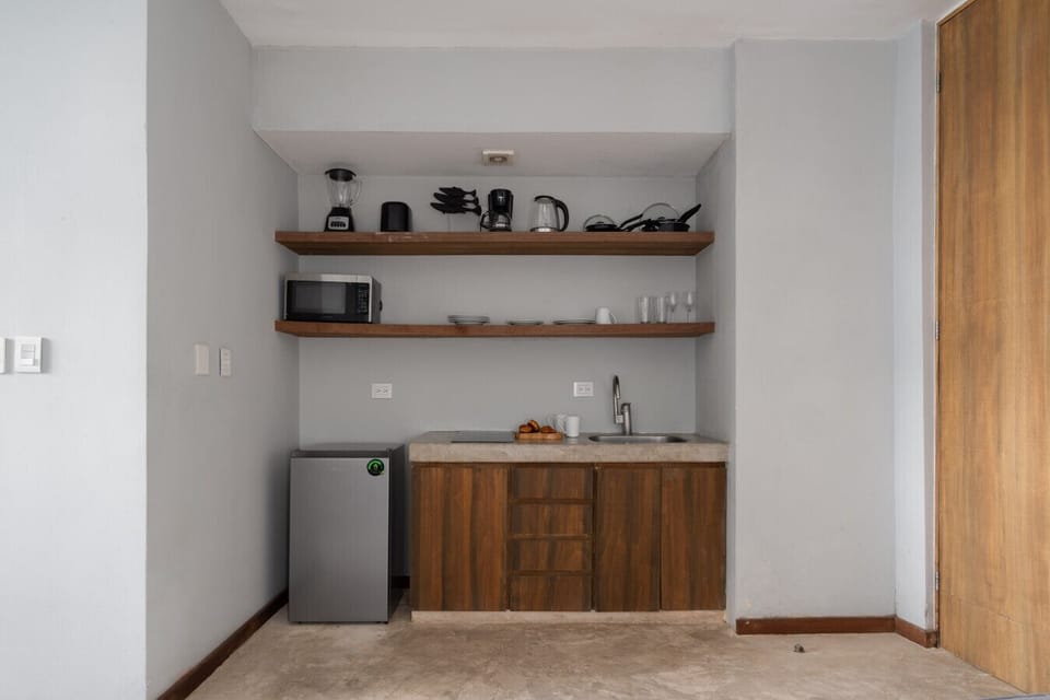 Cozy kitchen with all essentials: fridge, coffee maker, kettle, pots, and more.