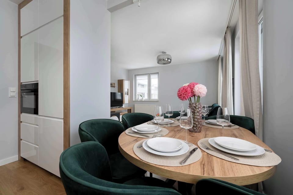 A close-up of the same dining table highlighting the plates and glassware. Decorative flowers bring a warm, welcoming tone. The setup looks refined and ready for guests.
