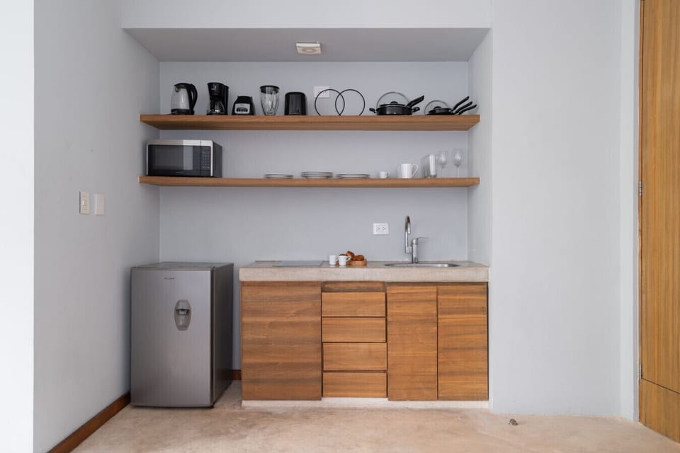 Cozy, fully equipped small kitchen with fridge, stove, cookware, and coffee maker.