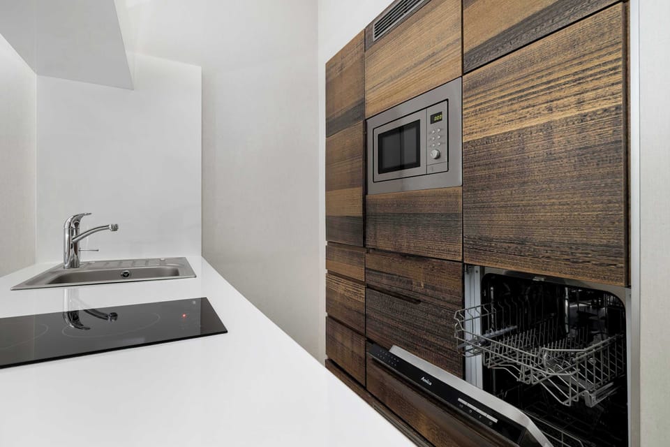 A small kitchenette area featuring a sink, stovetop, and wood-panel cabinets viewed from a close-up angle.