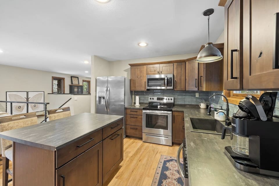 Warm wood cabinetry meets sleek stainless steel in this inviting kitchen. Features a flexible island dining area—the cozy heart of the home.