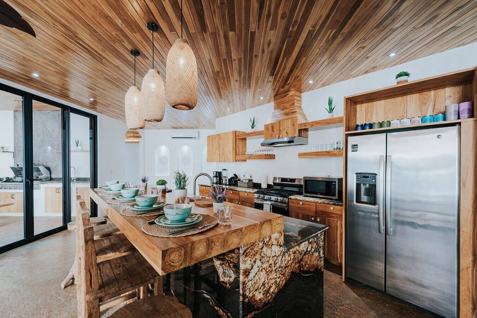 This bar-height dining area sits at the heart of the open kitchen, offering a warm and easy place to gather. With its teak ceiling, stylish lighting, and inviting setup, it’s a great spot for casual meals and conversation.