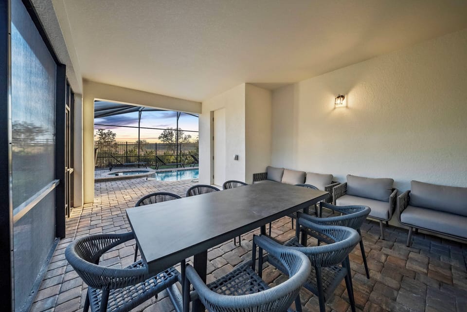 Experience a chic dining area featuring a sleek black table and cozy woven chairs, perfect for relaxed meals. Large windows offer breathtaking outdoor views and let in natural light, creating a warm, inviting atmosphere.