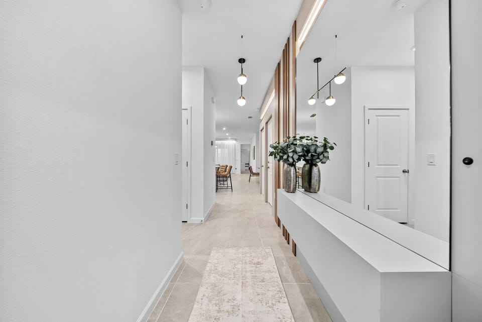 Welcome to a beautifully designed corridor with warm wood accents and sleek white walls that reflect natural light. A stylish console table adds sophistication, and a subtle floral arrangement refreshes your entryway.