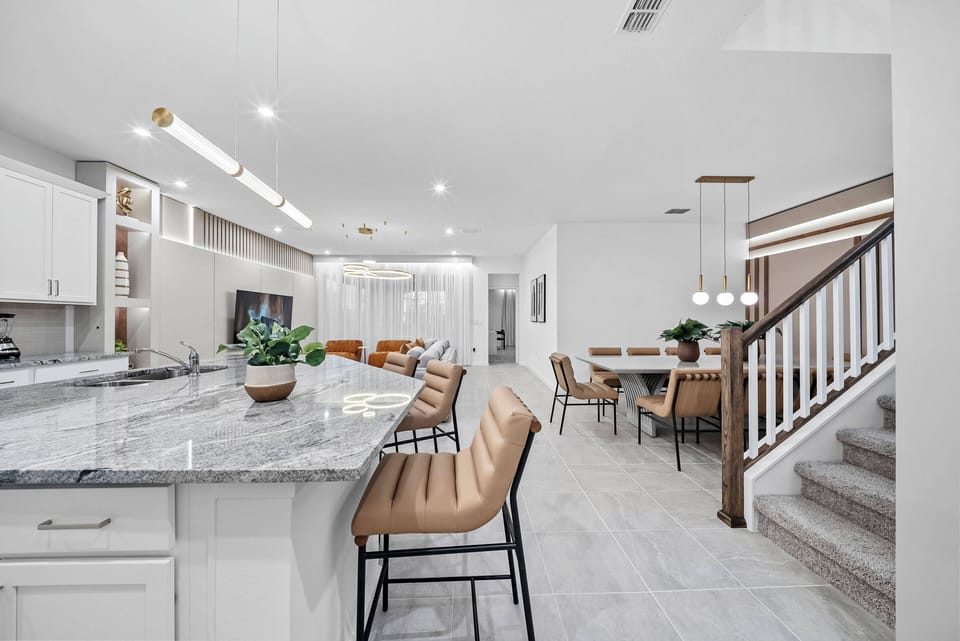 Experience a bright kitchen with sleek white cabinetry and a spacious granite island, ideal for morning coffee or casual meals. The warm tones in the bar seating and dining area create a cozy, inviting atmosphere for gatherings.