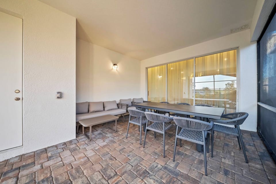 Experience this spacious outdoor dining area, filled with natural light from large glass doors. Savor meals at the sleek metal table, surrounded by modern seating on a chic tiled floor that creates a welcoming ambiance.