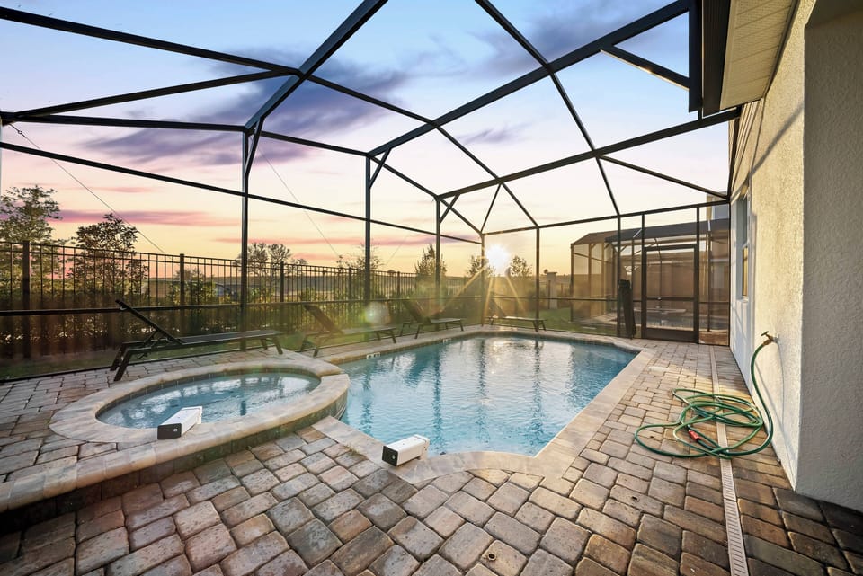 Step into your own private oasis featuring a sparkling pool surrounded by elegant stone paving. The spacious lanai creates a perfect spot to unwind as you enjoy stunning sunset views through the protective screen enclosure.
