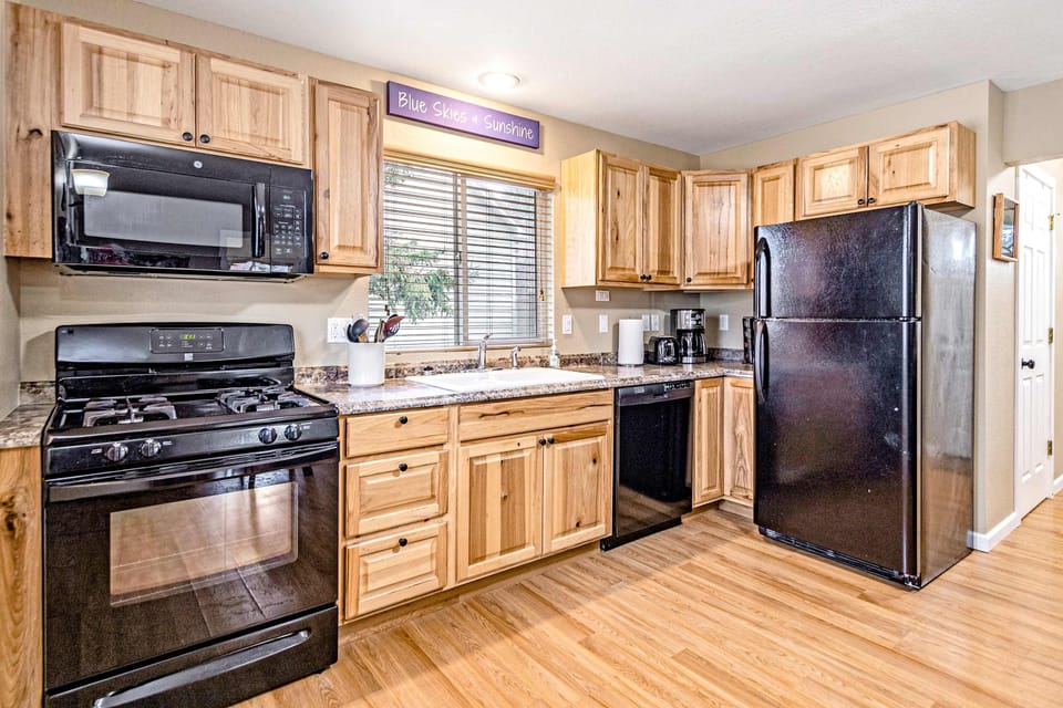 Full kitchen with knotty-hickory cabinetry, black appliances, gas range, and hardwood floors