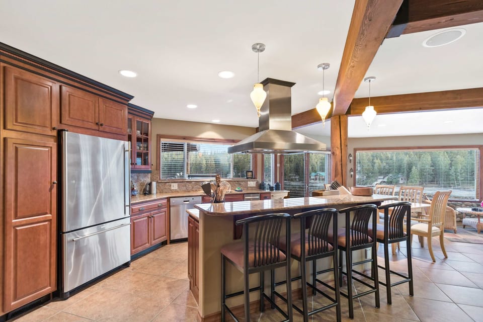 Chef's kitchen with granite island seating for four, stainless steel range hood, and river views