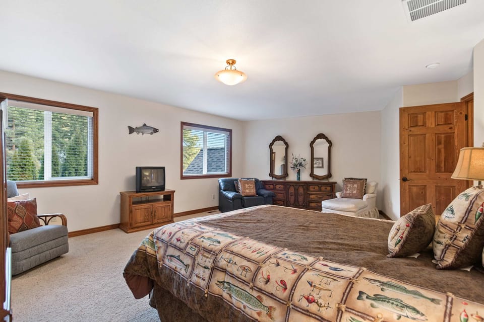 King bedroom with fishing-theme décor, two windows, leather chair, and walk-in closet door