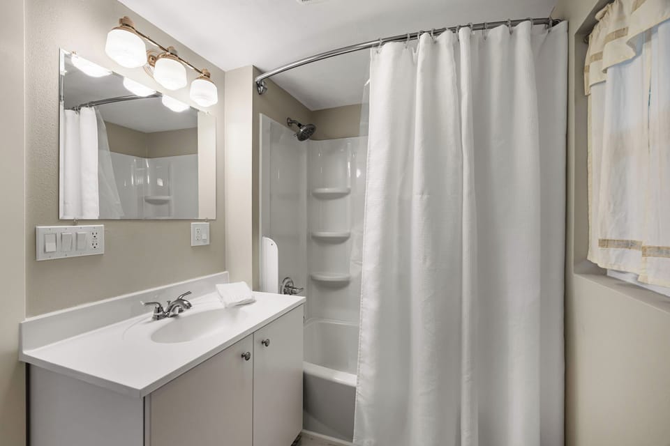 Bathroom with shower-tub combo and white vanity