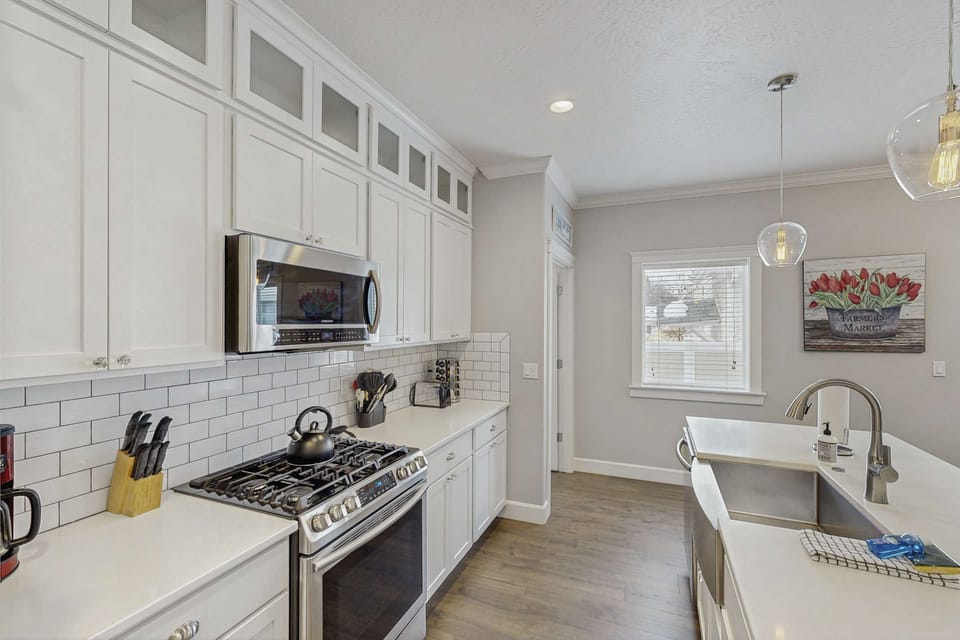 Bright kitchen with white shaker cabinets, subway tile backsplash, gas range, and pendant lights