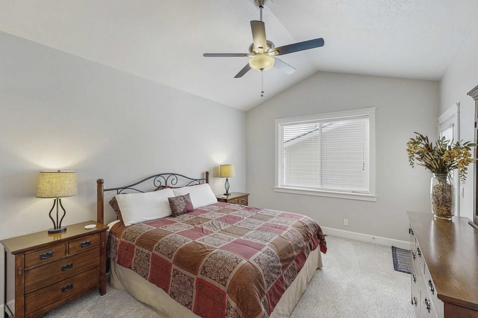 Queen bedroom with vaulted ceiling, ceiling fan, dual nightstands, and dresser