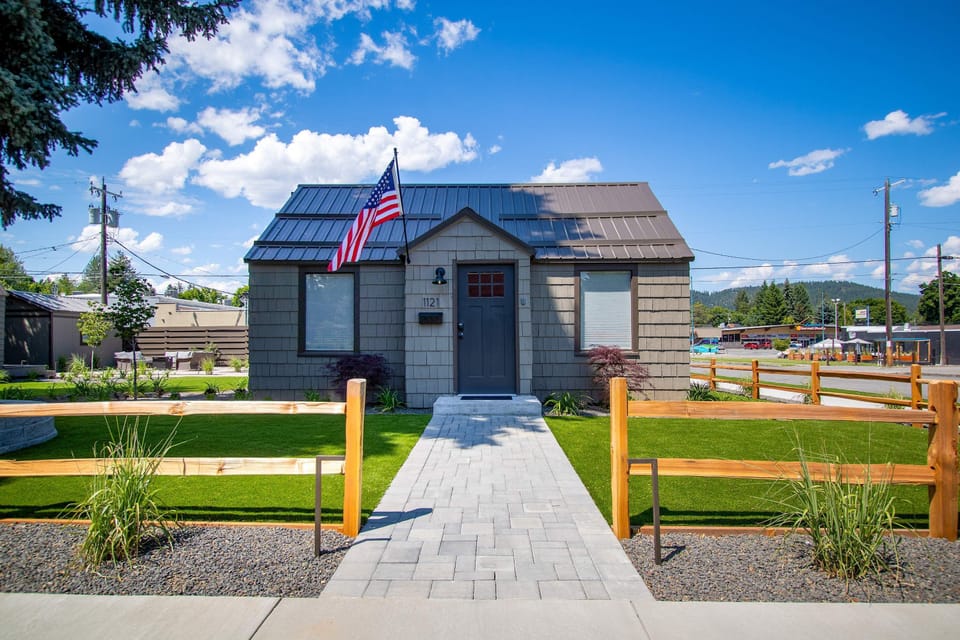 Sunny front entry with paver walkway, cedar split-rail fence, and freshly landscaped front yard
