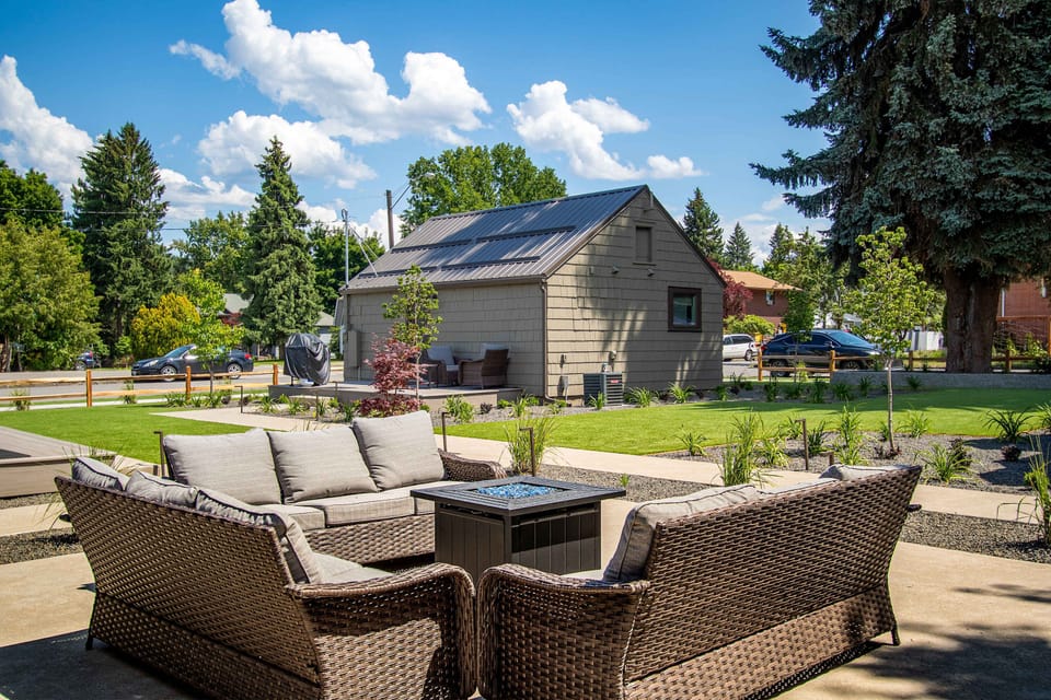 Sunny patio with wicker sectional seating and gas fire pit table, set in spacious landscaped yard