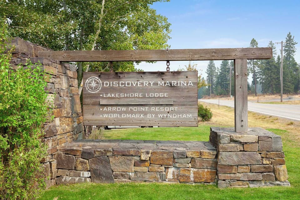 Rustic stone-and-timber Discovery Marina entrance sign surrounded by tall pines — you'll know you've arrived