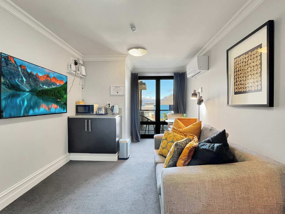 Open-plan space combining the living area and kitchenette, leading out to the balcony with lake views.