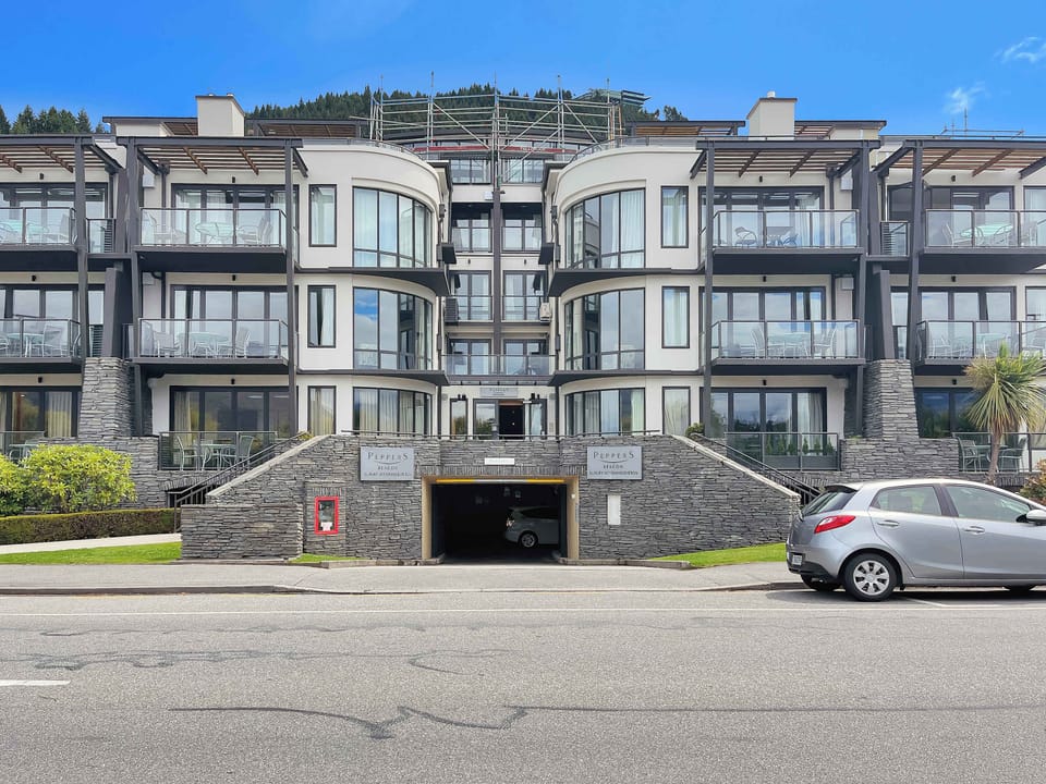 Front exterior view of the apartment complex with main entry and parking access.