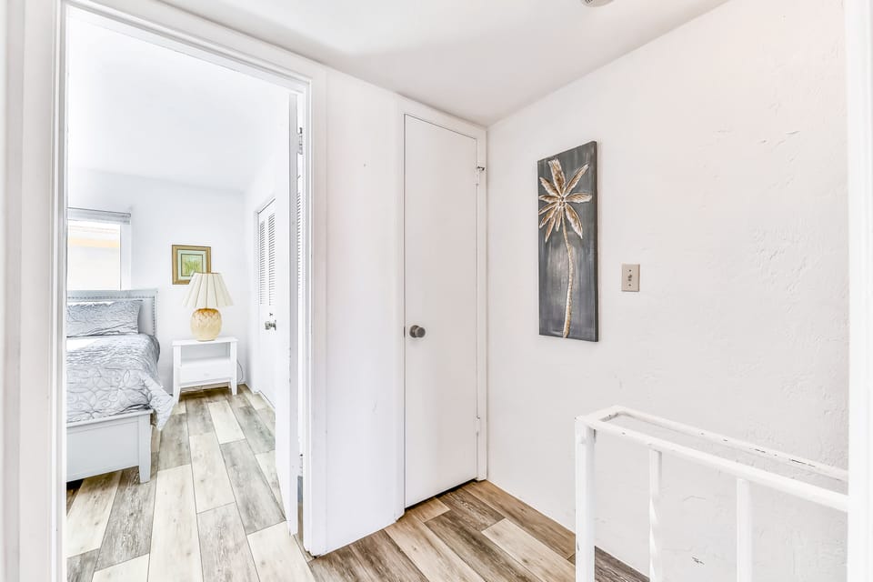 This bright hallway with beach-themed décor leads to cozy bedrooms, creating a light and airy retreat perfect for your relaxing beach stay.