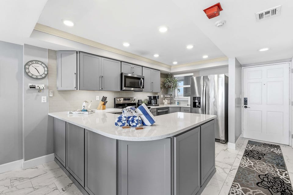 Cook with ease in this modern beach condo kitchen featuring stainless steel appliances, quartz countertops, and a spacious island. Perfect for family meals and entertaining after a fun-filled day at the beach.