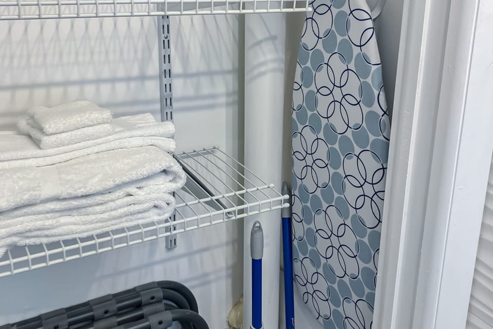 Conveniently stocked linen closet with fresh beach stay towels, an ironing board, and cleaning essentials—everything you need for a comfortable and carefree seaside getaway.