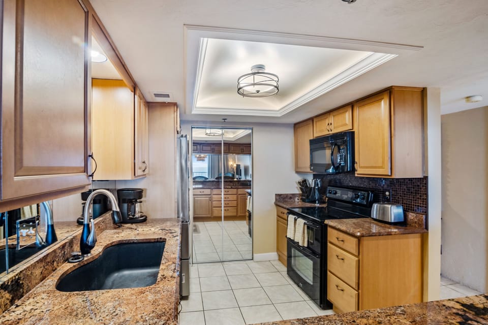 Well-appointed coastal kitchen featuring granite countertops, modern appliances, and ample storage. Designed for convenience and comfort, it's ideal for effortless cooking during relaxing beach stays by the ocean.