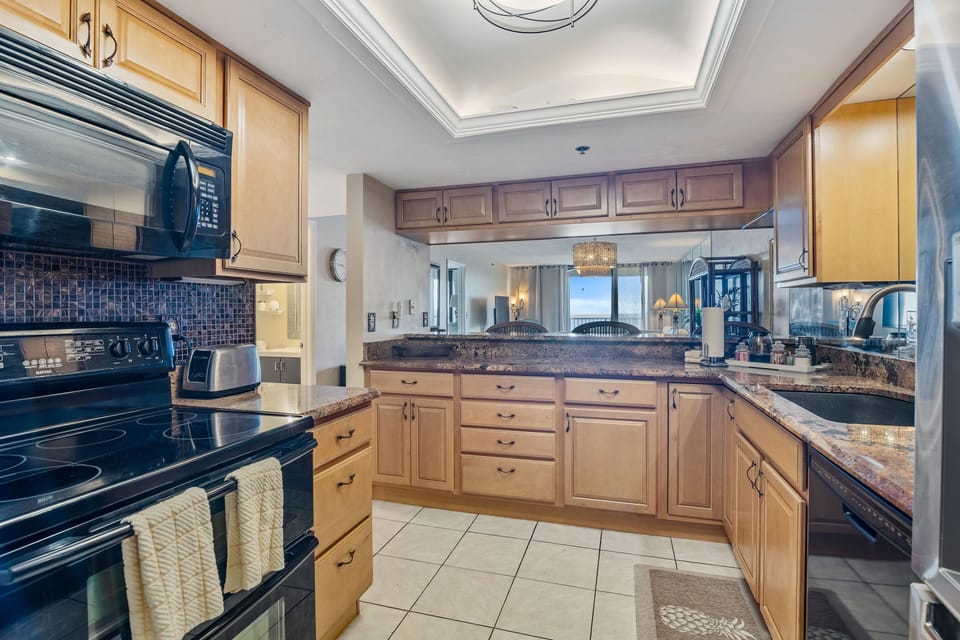 Open-concept coastal kitchen with granite countertops, modern appliances, and sightlines to the ocean-view living area. Designed for easy cooking and relaxed beach stays filled with comfort and coastal charm.