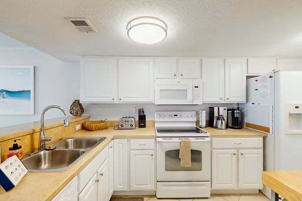 This fully equipped coastal kitchen is perfect for a relaxing beach stay, featuring modern appliances, ample counter space, and bright cabinetry—ideal for preparing meals after a day at the beach or enjoying a casual seaside breakfast.