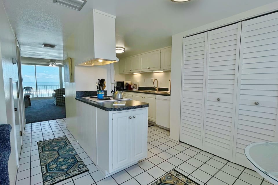 Prepare meals with ease in this bright, fully equipped kitchen featuring ample counter space and coastal charm, perfectly positioned just steps from the living area and balcony—ideal for a comfortable beachfront vacation stay.
