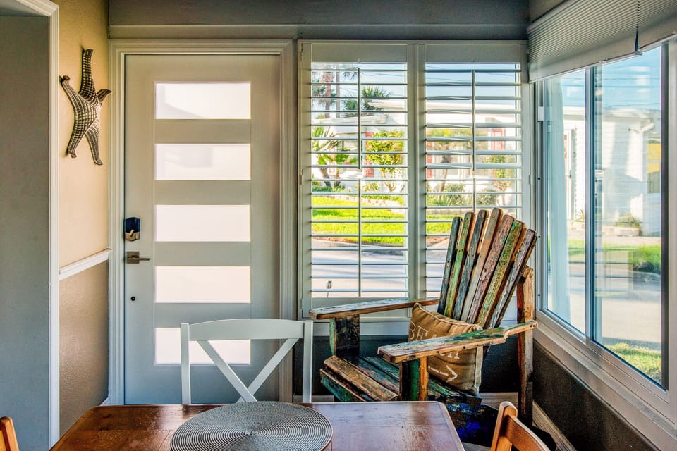 Start your beach stay in this bright coastal entry featuring a cozy breakfast nook, rustic beach-style chair, and large windows that invite in natural light—perfect for morning coffee before heading to the shore.