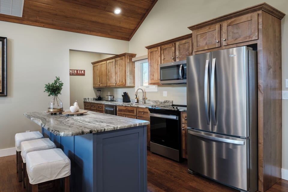 A bright, fully equipped kitchen with stainless steel appliances, spacious island seating, and everything you need for cooking, snacking, or gathering with family after a day in the mountains.