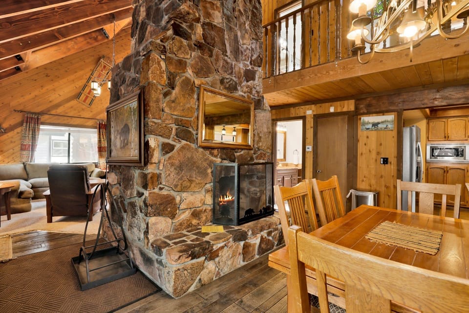 Cozy cabin living room with a stone fireplace, comfy seating, and a TV—perfect for relaxing evenings, movie nights, and unforgettable mountain getaways.
