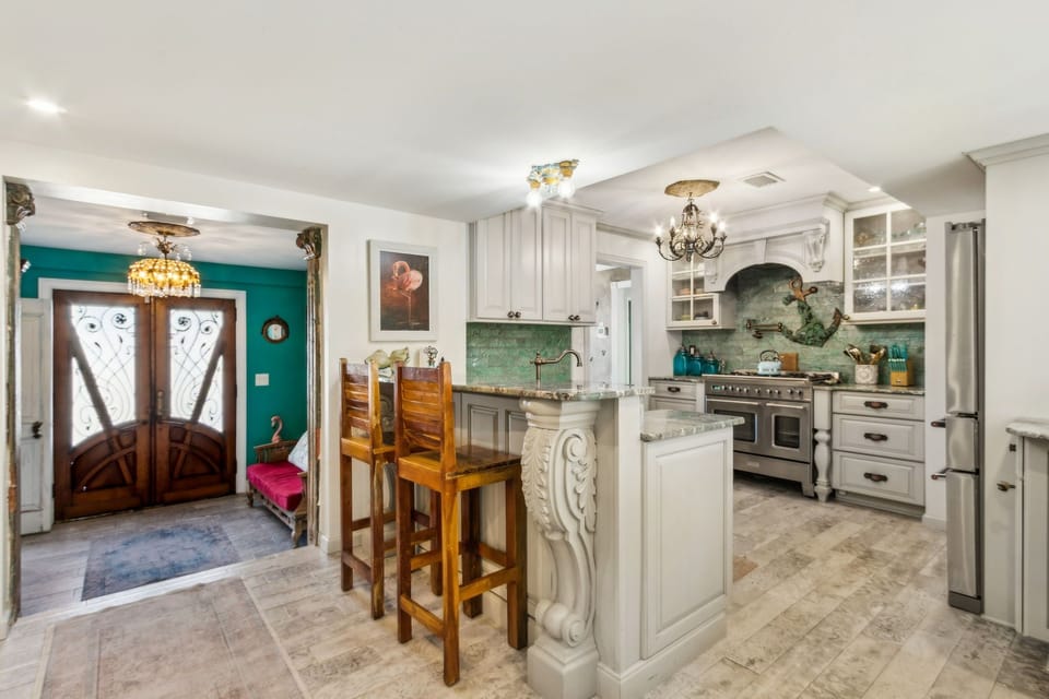 Updated Kitchen Featuring Granite Countertops, Double Ovens, an Oversized Refrigerator, a Large Farmhouse Style Sink, Barstool Seating for 4, and Charming Mermaid Design Touches