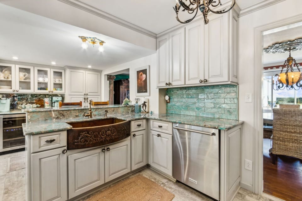Updated Kitchen Featuring Granite Countertops, Double Ovens, an Oversized Refrigerator, a Large Farmhouse Style Sink, Barstool Seating for 4, and Charming Mermaid Design Touches